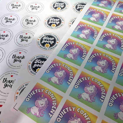 Sheets of custom silver vinyl stickers by Pure Pack in three designs, round thank you and logo labels and square full colour unicorn stickers
